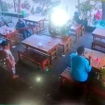 Dari tangkapan layar CCTV, tampak seorang bocah yang bersiap mengambil handphone milik pria berkaos biru.