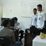 RCB (duduk membelangi kamera) saat diserahkan ke Rumah Detensi Imigrasi Surabaya.