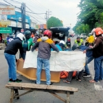 Petugas dibantu warga sedang menutupi jenazah korban kecelakaan akibat tertabrak truk.