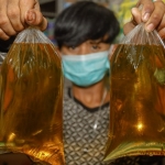 ILUSTRASI. Seorang penjual minyak goreng curah di Surabaya menunjukkan dagangannya. Foto: Jawa Pos