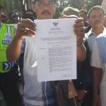 TUNJUKKAN: Seorang warga Desa Ketegan Tanggulangin menunjukkan SK Bupati Sidoarjo yang memerintahkan penghitungan ulang Pilkades Ketegan, kala aksi demo depan DPRD Sidoarjo, Senin (11/7) lalu. foto: MUSTAIN/ BANGSAONLINE