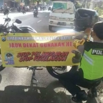 Brigadir Ari Yudiantono, saat memasang imbauan di sepeda motornya.