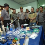 Petugas menujukan barang bukti narkoba jenis pil koplo, kondom, bong bekas sabu, serta senjata tajam. foto: RONY SUHARTOMO/ BANGSAONLINE
