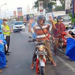 Pengendara roda 2 saat disemprot disinfektan oleh petugas Satlantas Polres Pasuruan.