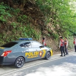 Anggota Satsabhara Polres Batu sedang melihat-lihat tebing di sepanjang Jalan Payung Kecamatan Pujon.