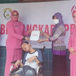 Istri Wakapolda Jatim saat memberi bantuan kepada penderita cerebral palsy. (foto: ist).