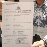 Pelapor ketika menunjukkan surat laporan polisi terkait dugaan penipuan dan penggelapan.