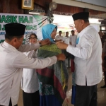 Pj Bupati Nganjuk Drs Sudjono saat mengalungkan serban secara simbolis ke calhaj tertua dan termuda. 