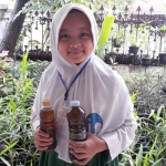 Afrina Karimah Nur Aisyah saat membawa produk jahe merah di halaman rumah.
