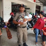 Petugas Satpol PP saat menggendong bayi yang dibawa pengemis untuk diamankan. foto: ist