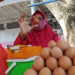Seorang pedagang telur ayam ras di Pasar Banyuwangi, Sri, saat menunjukkan sebutir telur.