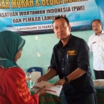 Ketua Panitia HPN 2019 PWI Lamongan, Nur Qomar Hadi saat menyerahkan bantuan bedah rumah kepada Nenek Gemi.