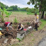 Petugas dari Polres Ngawi saat membantu warga membersihkan saluran air yang terkena limbah.