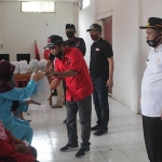 Ketua DPC PDIP Nganjuk, Tatit Heru Tjahjono didampingi Wakil Ketua DPD, Ida Bagus dan Wakil Bupati Marhaen saat membagikan sembako. (foto: BAMBANG/ BANGSAONLINE)