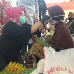 Lisdyarita saat memakaikan masker kepada salah satu pedagang Pasar Sawoo.