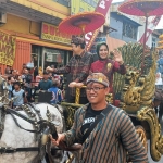 Wali Kota Mojokerto Ika Puspitasari bersama sang suami menaiki kereta kencana sambil menyapa warga saat kirab budaya.