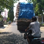 Pengendara motor tengah melintas di belakang truk bermuatan sekam. foto: HERI/ BANGSAONLINE
