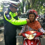 Petugas memberikan cara penggunaan helm yang benar.