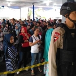 Petugas kepolisian standby melakukan pengamanan di gedung Kartini Malang. Tampak ratusan warga yang hendak menukarkan uang baru, Ahad (26/05). foto; IWAN IRAWAN/ BANGSAONLINE