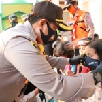 Kapolres Mojokerto AKBP Dony sedang mengenakan masker kepada seorang gadis kecil.
