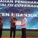 Pj Bupati Nganjuk Sri Handoko Taruna saat menerima penghargaan UHC pada peringatan HKH ke-60. Foto: Bambang D J/BANGSAONLINE