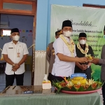 Bupati Bangkalan, R Abdul Latif Amin Imron saat menyerahkan potongan tumpeng krpada ketua pelaksana pembangunan Gedung TK Dharma Wanita Pesatuan 06 Jaddih,  Achmad Faisol.