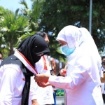 Gubernur Jawa Timur Khofifah Indar Parawansa saat meresmikan tim penegak disiplin protokol kesehatan di desa dengan ditandai pemakaian syal merah putih di Madiun, Jumat (18/9/2020). foto: ist/ bangsaonline.com