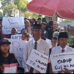 Mega Bagus Saputra (belakang, pakai kerpus) saat ikut demo mendukung bumbung kosong di KPU Gresik. Foto: SYUHUD/ BANGSAONLINE