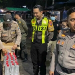 Petugas dari Polsek Simokerto saat menyita botol arak dari seorang warga di Jalan Kertopaten, Surabaya.