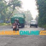 Kendaraan sarat muatan berhenti di tengah Jalan Mayjen Sungkono di sekitar Bukit Condrodipo, Desa Kembangan, karena tak kuat menanjak. Foto: SYUHUD/ BANGSAONLINE
