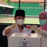 Bupati Arifin dan istri saat memasukkan surat suara ke dalam kotak surat suara. (foto: HERMAN/ BANGSAONLINE)