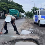 Petugas dari Satlantas Polres Situbondo saat memberi tanda terhadap jalan rusak.