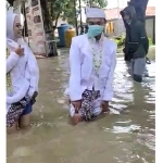 Pasangan calon suami istri menerjang banjir saat akan ijab kabul di KUA Benjeng. (foto: ist)
