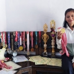 Mila Karmila (21), Atlet Kota Probolinggo bersama sejumlah piala, medali, hingga piagam penghargaan yang berhasil ia koleksi berkat prestasinya di bidang olah raga.