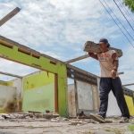 Seorang pekerja saat melewati bangunan pasar Ngadiluwih yang sudah mulai dibongkar. (Ist)