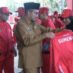 Bupati Sumenep, Achmad Fauzi Wongsojudo saat memasangkan jaket kepada atlet secara simbolis pada acara pelepasan Kontingen Sumenep Porprov Jatim ke-IX
