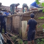 Warga bersama babinsa gotong royong membenahi rumah warga yang tertimpa pohon tumbang.