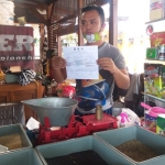 Penjual pakan burung, Oky Berli Saputra (31), saat menunjukkan surat peringatan dari Satpol PP Pemkot Batu.