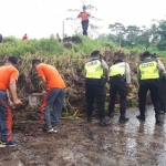 Para petugas gabungan sedang sibuk membersihkan longsoran sawah yang menutup akses jalan ke dua desa tersebut.