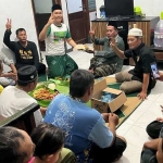 Ketua Umum RGS Indonesia, Taufiq Muhammad disaksikan Pendiri RGS, Moh Khozin memberikan potongan tumpeng kepada tim relawan saat syukuran di posko Dusun Kradenan. Foto: SYUHUD/ BANGSAONLINE