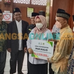 Wakil Bupati Gresik, Aminatun Habibah, didampingi Ketua PD DMI Gresik, Zainal Abidin, saat menyerahkan bantuan kehormatan kepada imam masjid. Foto: SYUHUD/BANGSAONLINE