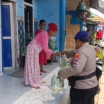 Anggota saat membagikan sayur ke salah satu warga