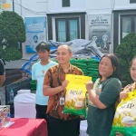 Kasi Intelejen Kejari Kabupaten Kediri, Iwan Nuzuardhi foto bersama warga pembeli beras murah. Foto: Muji Harjita/Bangsaonline.