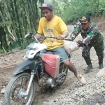 Satgas TMMD 105 Trenggalek bahu-membahu dengan masyarakat mengangkut material semen dengan menggunakan sepeda motor.