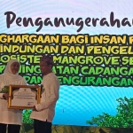 Rektor UTM, Prof. Dr. Safi, S.H., M.H., saat menerima penghargaan dari Gubernur Khofifah dalam Festival Mangrove ke-8 yang digelar di Pesisir Mlajah.