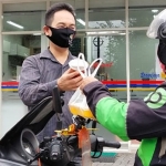 Daniel Lukas Rorong, Humas PDOI Jatim saat membagikan masker dan hand sanitizer pada masyarakat, termasuk ojol dan pengendara motor yang melintas, Minggu (10/1/21). foto: istimewa