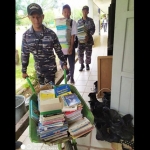 Para Prajurit KRI Yos Sudarso-353 sedang mengangkut ratusan buku ke dalam sekolah.