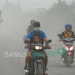 Pengendara yang melintas di jalan antara Betoyo-Pecuk, Manyar, Gresik  mengenakan masker untuk meminimalisi debu yang terhirup. foto: SYUHUD/BANGSAONLINE