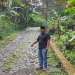 Warga menunjukkan kondisi jalan penghubung di Desa Ngantungan yang masih berupa makadam.