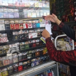 Petugas saat menempelkan stiker dalam operasi pita cukai rokok ilegal. Foto: Hendro Suhartono/BANGSAONLINE